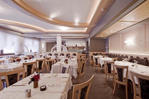 une salle à manger avec des tables et des chaises blanches dans l'établissement Liz Hotel & Apartments, à Predazzo