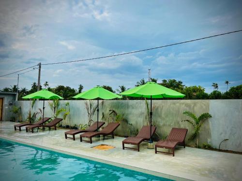 a group of chairs and umbrellas next to a pool at Doppel Gangs Arugambay in Arugam Bay