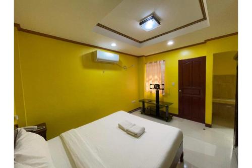 a room with a bed with yellow walls and a door at Casa Venicia Caticlan in Boracay