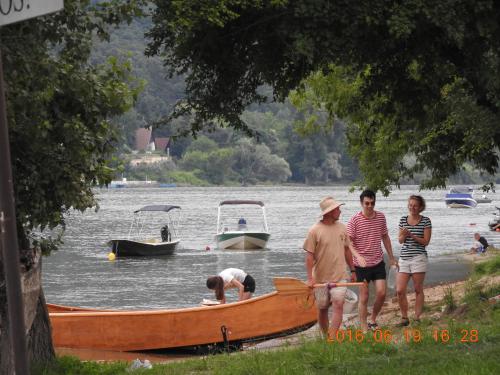 a group of people standing next to a boat in the water at Dunakanyar Apartman in Pilismarót