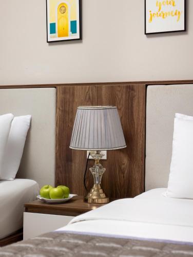 a bed with a lamp and a plate of fruit on a table at Cat Ba Seoul 2 Hotel & Apartment in Cat Ba