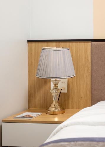 a lamp sitting on a table next to a bed at Cat Ba Seoul 2 Hotel & Apartment in Cat Ba