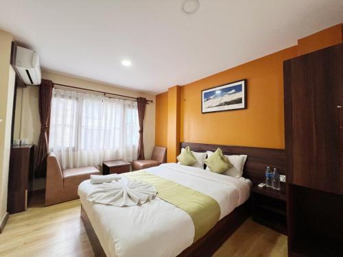 a hotel room with a large bed and a chair at Holiday Hostel Kathmandu in Kathmandu