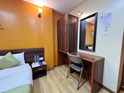 a hotel room with a desk and a bed and a mirror at Holiday Hostel Kathmandu in Kathmandu