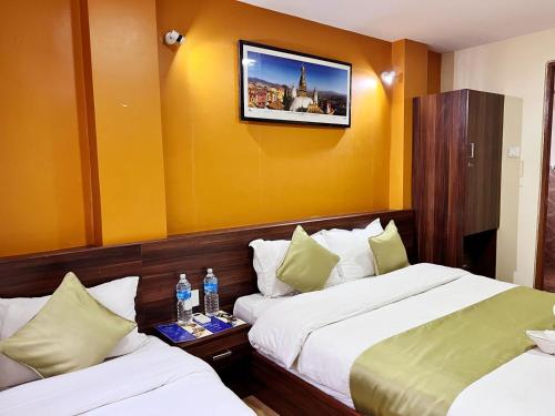 a hotel room with two beds and a tv on the wall at Holiday Hostel Kathmandu in Kathmandu