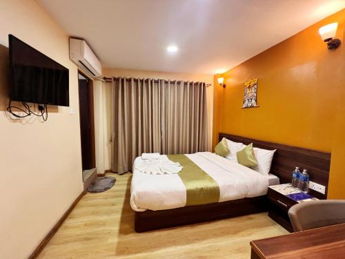 a hotel room with a bed and a television at Holiday Hostel Kathmandu in Kathmandu