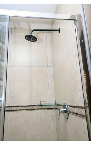 a shower with a glass door and a shower head at Mbuso Guest Lodge in Richards Bay