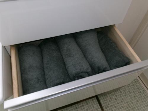 a row of grey towels in a drawer at Guest House OHANA in Kami-furano