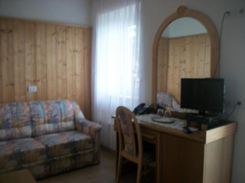 a living room with a desk with a television and a couch at Agri-park Casa Miramonte in Ronzone