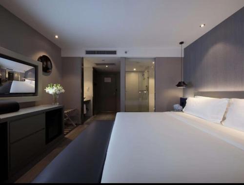 a bedroom with a large white bed and a television at Orange Hotel Beijing Shangdi Huandao in Beijing