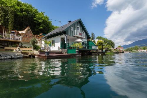 a house on a dock on a body of water at Smileys Seehäuschen in Seeboden
