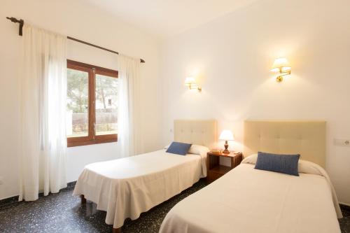 two beds in a white room with a window at Cabot Villa Can Borras in Port de Pollensa