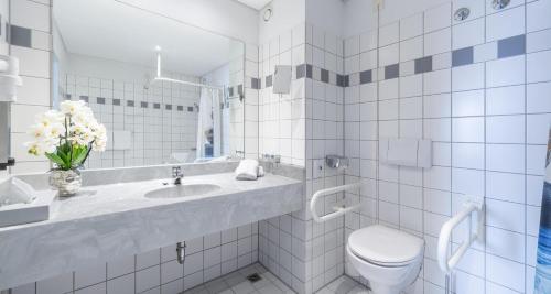 a white bathroom with a toilet and a sink at Best Western Plaza Hotel Zwickau in Zwickau