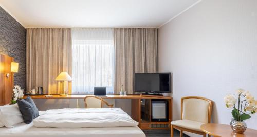 a hotel room with a bed and a desk with a tv at Best Western Plaza Hotel Zwickau in Zwickau