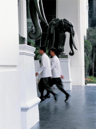 two men walking past a statue in front of a building at Grand Hyatt Erawan Bangkok in Bangkok