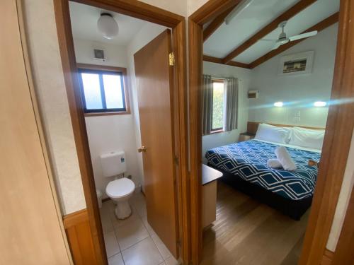 a small bedroom with a bed and a toilet at Yea Riverside Caravan Park in Yea