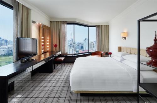 a hotel room with a bed and a flat screen tv at Grand Hyatt Erawan Bangkok in Bangkok