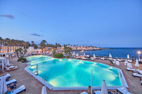 a large swimming pool next to the ocean at AluaSoul Menorca - Adults Only in S'Algar