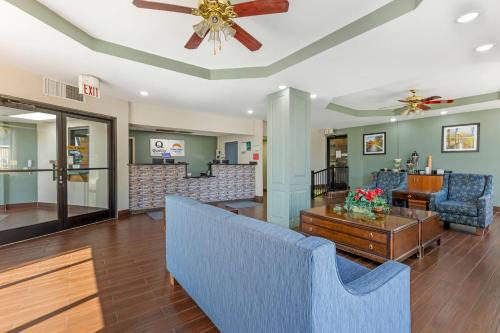 a living room with a ceiling fan and blue chairs at Quality Inn & Suites Orangeburg in Orangeburg