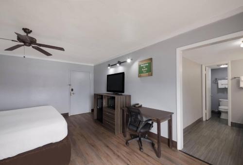 a bedroom with a bed and a desk with a television at Econo Lodge Austin North near The Domain in Austin