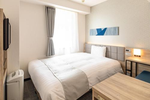 a hotel room with a bed and a desk and a window at Comfort Hotel Hiroshima Otemachi in Hiroshima