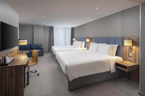 a hotel room with two beds and a desk at Hilton Garden Inn London Heathrow Terminal 2 and 3 in Hillingdon