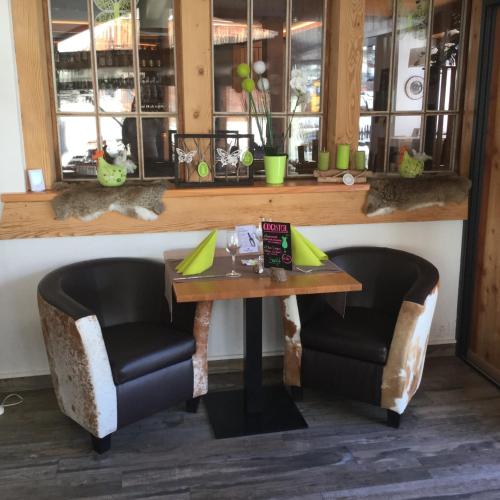 a table and two chairs in a room with windows at Hôtel Dents de Veisivi in Haudères