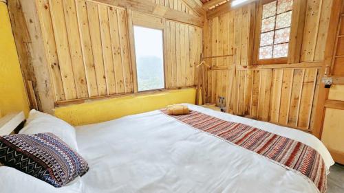 a bedroom with a white bed in a room with wooden walls at À Lôi Homestay Lô Lô Chải in Loung Co