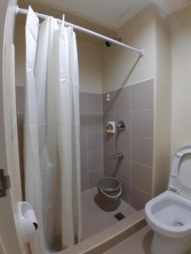 a bathroom with a toilet and a shower with a shower curtain at The Suite Pod I CDO CondoStaycation in Cagayan de Oro