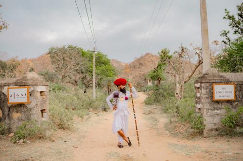 a woman walking down a dirt road with a pole at Aloof Jungle Lodge in Ghānerao