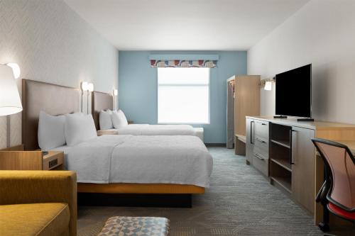 a hotel room with a bed and a flat screen tv at Home2 Suites By Hilton Austin South in Austin