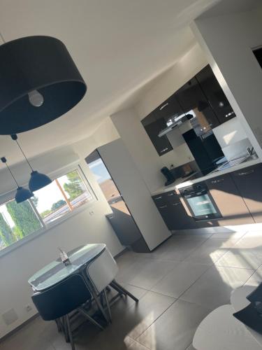 une cuisine avec des armoires noires, une table et des chaises dans l'établissement Appartement les 3 horloges, à Marseillan