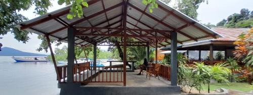 a pavilion with a table and chairs on the water at Bunaken Sunrise Beach in Manado