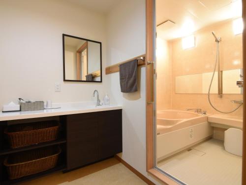 a bathroom with a tub and a sink and a shower at Awa Ikeda Station Hotel Eleven in Miyoshi