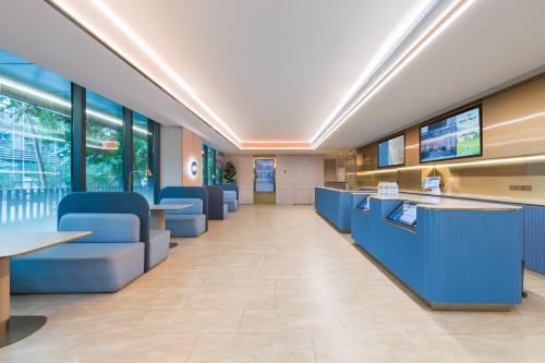 a lobby of a hospital with blue chairs and tables at Hanting Hotel Beijing Jiaotong University in Beijing