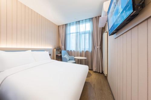 a hotel room with a bed and a tv at Hanting Hotel Beijing Jiaotong University in Beijing