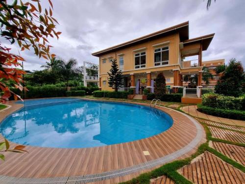 a house with a swimming pool in front of a house at VERDANT by Vista Manors Deluxe Rooms with Balcony, Gym and Swimming Pool in Puerto Princesa City