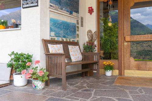 a wooden bench sitting on a porch with flowers at Pension Baumgarten in Naturno
