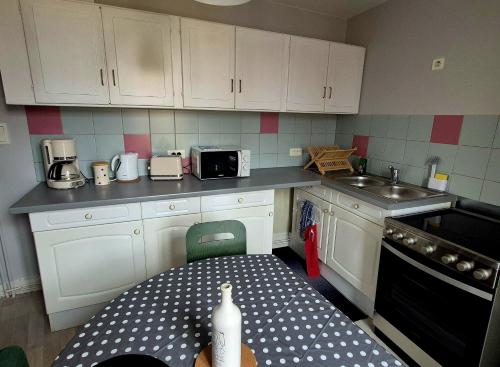 a kitchen with white cabinets and a table and a sink at Chez Armande in Châtel-Guyon