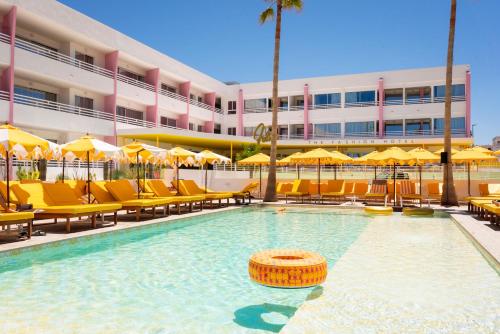 a swimming pool with chairs and umbrellas in front of a hotel at Los Felices Ibiza in San Antonio Bay