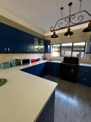 una cucina con armadi blu e piano di lavoro bianco di Die Blou Huis a Clarens