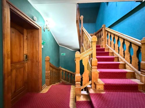 a staircase with red carpeting and a wooden door at Heban Hotel in Toruń