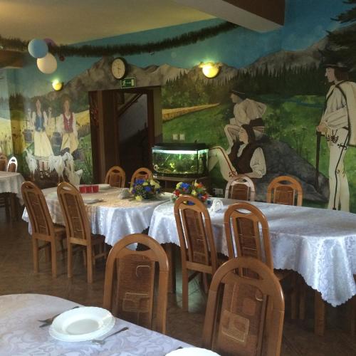 a room with tables and chairs and a painting on the wall at Ośrodek Wypoczynkowy Bernadetta in Murzasichle