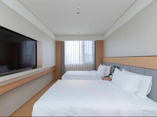 a hotel room with two beds and a flat screen tv at JI Hotel Beijing Huilongguan West Street全季北京回龙观西大街酒店 in Beijing