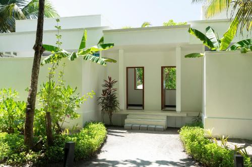 a white house with trees and plants in front of it at Dhigali Maldives - A Premium All-Inclusive Resort in Raa Atoll