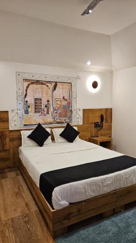 a bedroom with a large bed with a painting on the wall at Santkrupa Villa Resort in Nakhtarāna