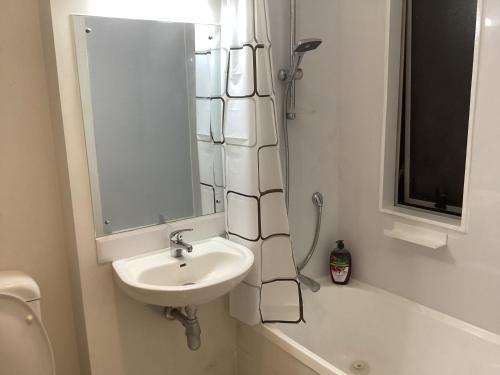 Un baño con lavabo, espejo y bañera. en 6 Scotia, en Auckland