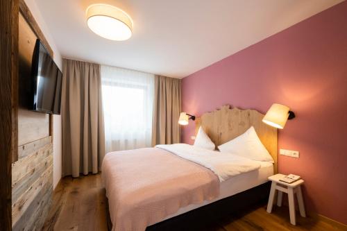 a hotel room with a bed and a flat screen tv at Sepp & Hannis Suiten im Dorf in Neustift im Stubaital