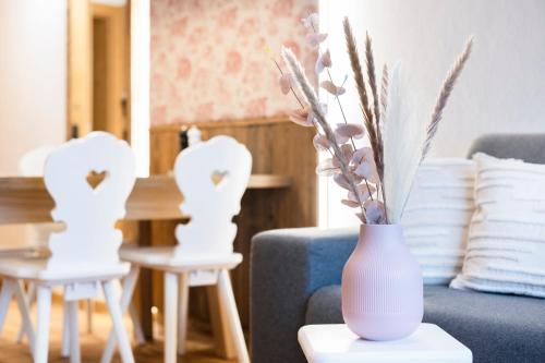 a vase with flowers on a table in a living room at Sepp & Hannis Suiten im Dorf in Neustift im Stubaital