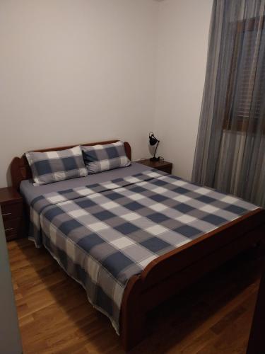 a bedroom with a bed with a blue and white checkered blanket at Apartman Elena Budva in Budva